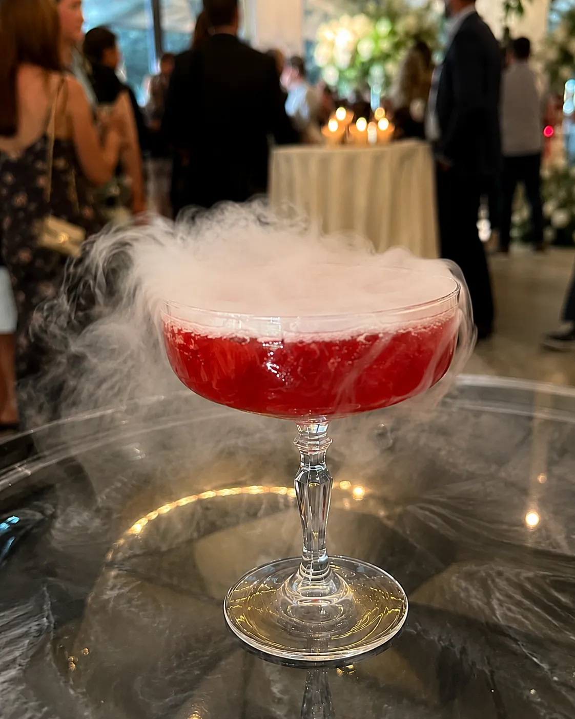 Red cocktail served with a theatrical dry-ice smoke effect